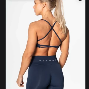 Mörkblå sporttopp från Relode - Säljer en mörkblå sporttopp från Relode med korsade band i ryggen. Materialet är mjukt och stretchigt för bästa komfort.