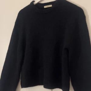 Svart stickad tröja från Gina Tricot - Säljer en stilren svart stickad tröja från Gina Tricot i storlek XS. Tröjan har en klassisk rund halsringning och långa ärmar, perfekt för kyligare dagar. Den är mjuk och bekväm att bära. Passar utmärkt till både jeans och kjol.