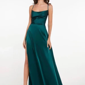 Grön långklänning med snörning - Elegant grön långklänning i satin med smala axelband och djup slits. Klänningen har en öppen rygg med snygg snörning som ger en unik look. Perfekt för speciella tillfällen.