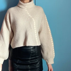 Beige stickad polotröja från Monki - Säljer en snygg beige stickad polotröja från Monki. Tröjan är croppad med långa ärmar och har en mysig polokrage. Nästan aldrig använd.