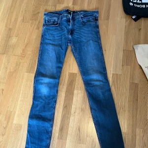 Replay Anbass W33 L36 - Snygga blå jeansbyxor med en klassisk femficksdesign. De har en dragkedja och knapp framtill. Perfekta för en avslappnad stil.