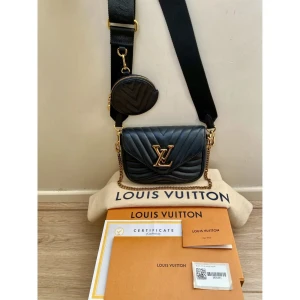 Äkta Svart axelväska från Louis Vuitton - Snygg svart axelväska från Louis Vuitton med quiltad design och guldfärgade detaljer. Väskan har en justerbar axelrem och en liten rund plånbok fäst vid remmen. Perfekt för att bära dina nödvändigheter med stil.   Betalningen via Revolut ✅