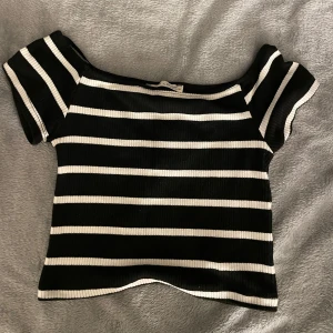 Svart och vit randig topp från Pull&Bear - Säljer en snygg svart och vit randig topp från Pull&Bear. Toppen är ribbad och har korta ärmar med en offshoulder-design. Använd ett fåtal gånger och är därför i ett fint skick ⭐️Den är i storlek M men passar S! 
