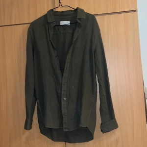 Olivgrön skjorta från Zara Man - Snygg olivgrön skjorta från Zara Man med klassisk krage och knappar framtill. Skjortan har långa ärmar och är perfekt för en stilren look. Passar bra till både jeans och chinos.