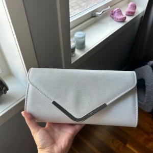 Balväska - Superfin väska som jag använde förra året på min bal, mycket ljus silvrig/vit färg som skimrar. Enbart använd av mig den gången och tjejen jag köpte den av hade också bara använt den en gång på hennes bal. Kan användas både utan och med axelband.