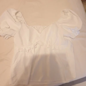 Vit blus - Vit blus med puffärmar och spetsdetaljer vid urringningen. Blusen har en lös passform lätt på kroppen.säljs för 50