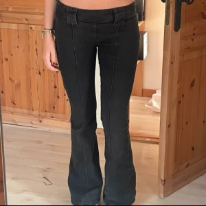 Svarta lågmidjade bootcut jeans - Säljer ett par snygga svarta jeans med låg midja och bootcut-stil. De har en dragkedja framtill och är i bra skick. Perfekta för en avslappnad men stilren look! Innerbenslängd 83 cm, midjemått 38 cm😊