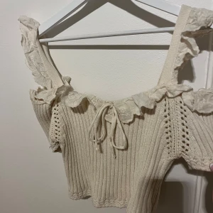 kräm vit/ beige topp - Kortare volang topp med rosett. Priset kan diskuteras 