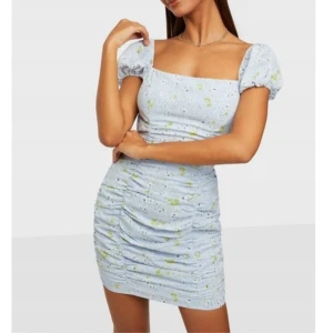 Blommig ljusblå klänning med snörning - Ljusblå klänning med blommigt mönster från märket Kiss The Sky. Köpt från antingen Asos eller Nelly. Klänningen har puffärmar och en snörning i ryggen. Storlek XL men passar också mig som i vanligtvis är M. Använd en gång, fint skick. 