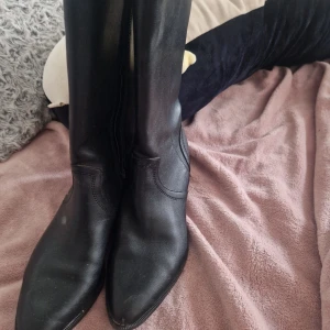 Svarta skinnstövlar med dragkedja - Säljer ett par stilrena svarta stövlar i skinn. De har en praktisk dragkedja på sidan för enkel på- och avtagning. Perfekta för både höst och vinter, och de ger en elegant touch till vilken outfit som helst.