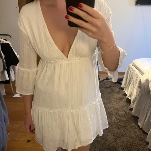 Vit klänning  - Kort klänning med trekvartsarmar. Vringning. 