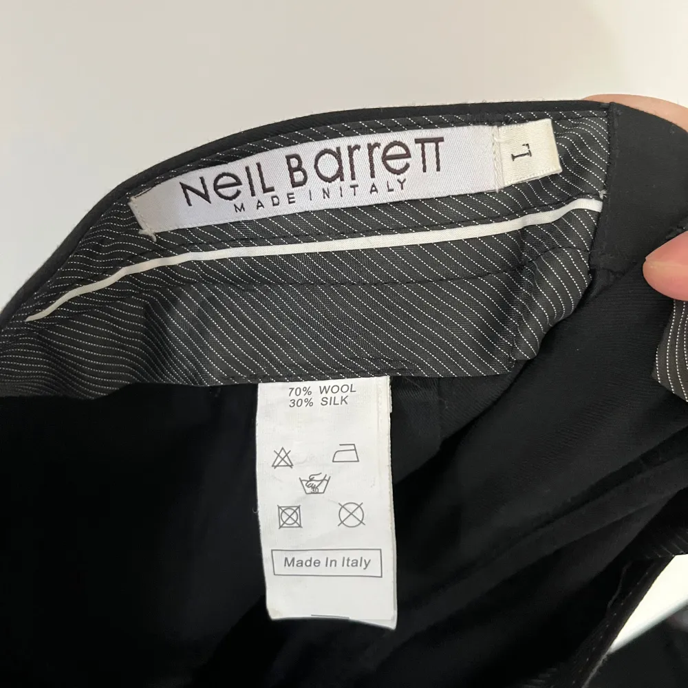 Säljer ett par stilrena svarta shorts från Neil Barrett, tillverkade i Italien. De är gjorda av 70% ull och 30% silke, vilket ger dem en lyxig känsla. Shortsen har en klassisk design med knappar och en snygg uppvikt kant. Perfekta för en elegant sommarlook!. Shorts.