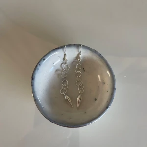 Silvriga örhängen med kedjor och koner - Säljer ett par coola silvriga örhängen med kedjor av små ringar och spetsiga nitar längst ner. Perfekta för att ge din outfit en edgy touch! Passar både till vardags och fest.