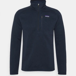Patagonia - Den är som på bilden fast ingen ficka. Är bara sämst på att fota. Den har ett tunt lager fleece på insidan.
