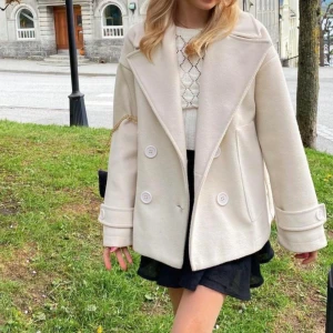 Design by si kappa - Vit/begie kappa från design by si. Säljer för den inte kommer till användning. Har lite sminkfläckar på insidan av kragen som jag inte lyckats få bort men som inte syns alls när man har på sig den men därav priset.🌸 nypris:757kr