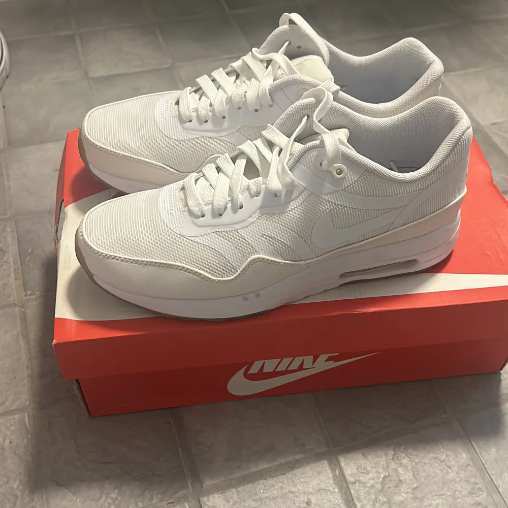 Säljer ett par vita Nike Air Max 1 PRM i nyskick. De är superfräscha och har en snygg, stilren design med snörning. De lyser i mörkret. Skorna kommer i originalkartong.. Skor.