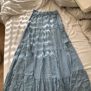 Ljusblå långkjol från ONLY - Säljer en superfin ljusblå långkjol från ONLY. Kjolen har en avslappnad passform med elastisk midja för extra komfort. Perfekt för sommarn! Materialet känns lätt och luftigt, vilket gör den idealisk för varmare väder.