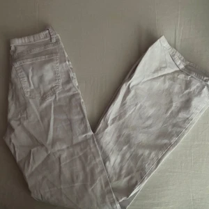Beige jeansbyxor - Säljer ett par snygga vita utsvängda jeansbyxor. De har en klassisk femficksdesign med knapp och dragkedja framtill. Perfekta för en avslappnad stil!