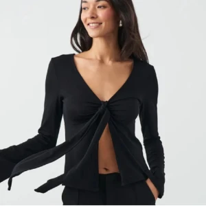 Svart knytblus från Gina Tricot - Säljer just nu denna snygga Design By Si-liknande svarta knytblusen från Gina Tricot i storlek S. Blusen har en v-ringad design och långa ärmar. Använd 3 gånger!!✨Perfekt till både vardag och fest!!🖤 (Org. pris 299kr) 