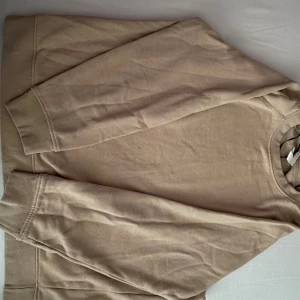 Beige sweatshirt - Säljer en snygg beige sweatshirt i bomull. Den är perfekt för både höst och vår med sin mjuka och bekväma passform. Tröjan har långa ärmar och ribbade muddar vid ärmslut och nederkant. Passar perfekt till vardags eller en avslappnad dag ute.