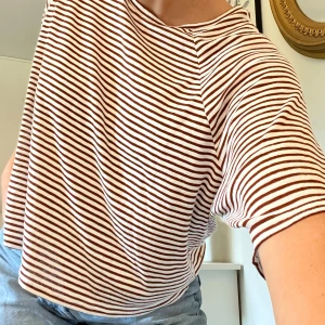 Randig tröja - Oversize t-shirt i grövre textur och mörkbruna ränder från weekday. Frakt tillkommer på 58kr 🫶🏻