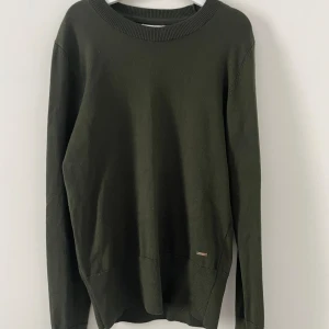 Stickad tröja  - Mycket gott skick, använd endast ett fåtal gånger, silvriga detaljer vi armsluten (knappar med hals).