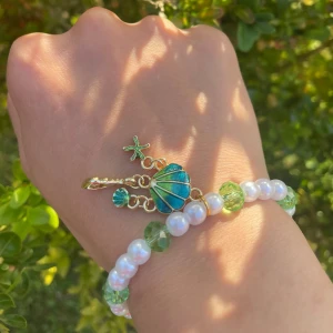 Armband  - Ett färgglatt armband med blågrön berlock 