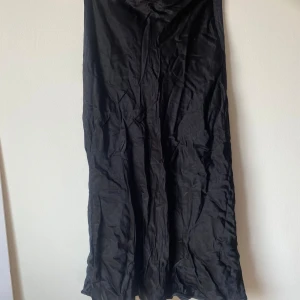 Svart långklänning från Zara - Säljer en elegant svart långklänning från Zara. Klänningen är i storlek XS och har en stilren design med en dragkedja i ryggen. Perfekt för festliga tillfällen eller en kväll ute. Materialet känns mjukt och bekvämt mot huden.