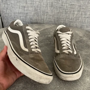 Vans Old Skool - Säljer ett par grå Vans old skool i okej skick. De har en klassisk design med vit sula och vita snören. Perfekta för vardagsbruk och ger en skön, avslappnad stil.