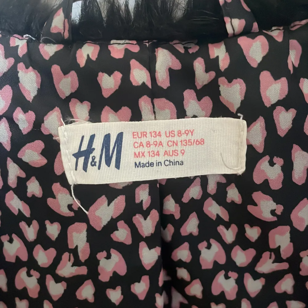 Säljer en superfin svart pälsväst från H&M. Den är perfekt för att ge din outfit en extra touch av stil. Västen är fodrad med ett mönster av rosa och vita hjärtan, vilket gör den både söt och trendig. Perfekt för höst och vinter!. Jackor.