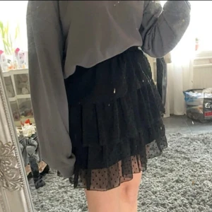 Svart volangkjol med prickigt mönster - Säljer en superfin svart kortkjol med volanger och ett sött prickigt mönster. Kjolen har en elastisk midja för en bekväm passform och är perfekt för både fest och vardag. Den är i nyskick och redo att bli en del av din garderob! storlek XS men passar även S.