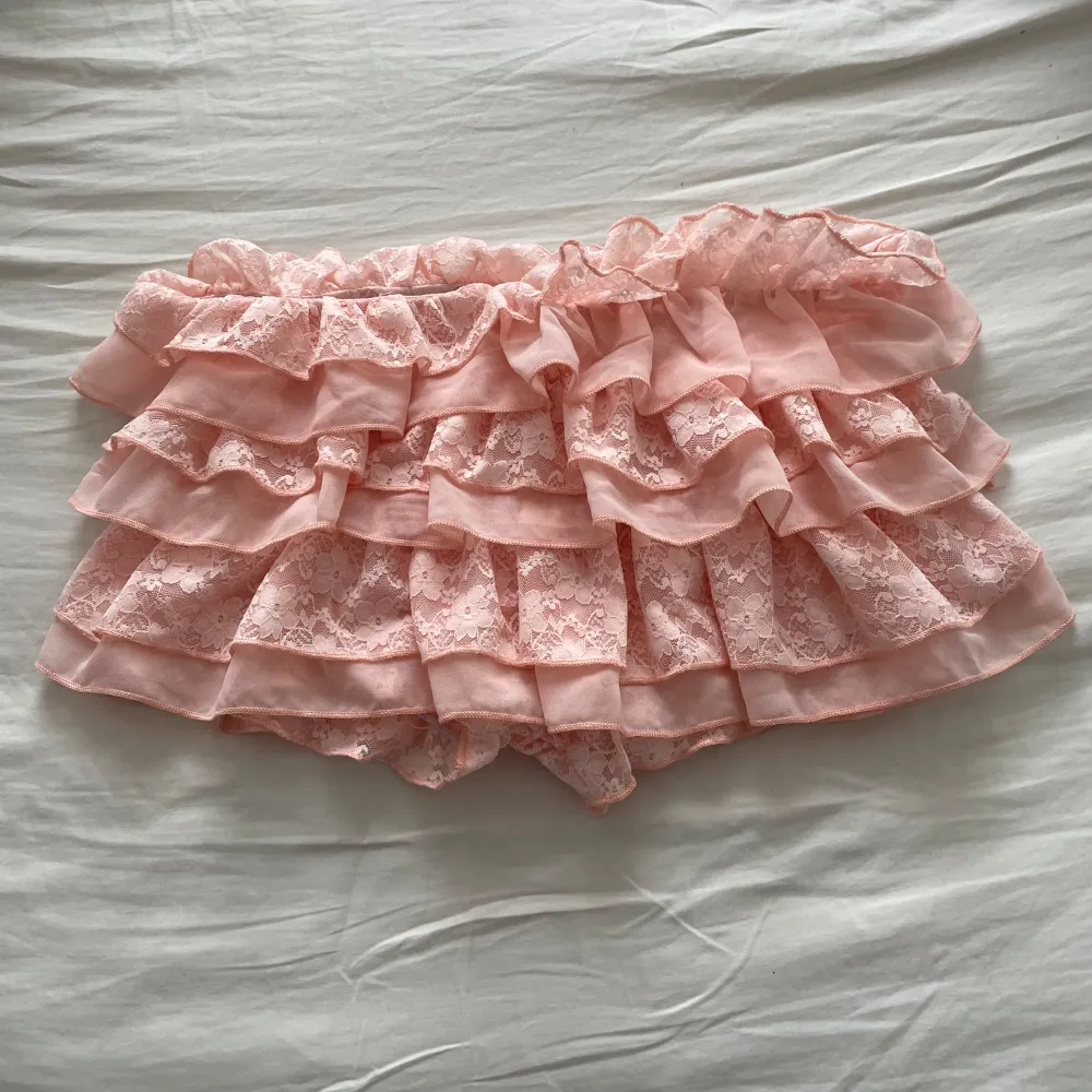 Säljer en superfin rosa kortkjol med volanger. Kjolen har flera lager av volanger som ger en söt och lekfull look. Den har shorts under och är i strl L, men passar även mindre storlekar. väldigt stretchigt material. Aldrig använd . Kjolar.