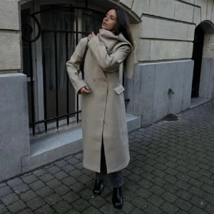 NAKD kappa - Nyköpt lång beige kappa från NAKD, med tillhörande scarf, som är borttagbar. I nyskick. Nypris 1100, med prislappen kvar. Just nu fri frakt!