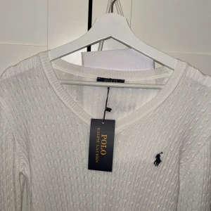 Ralph Lauren stickad tröja  - Hej, säljer den här super snygga vita stickade tröjan från Ralph Lauren med v-neck. Den är i storlek L men den passar mer som M då den är i ett stretchig material. Fick den som present då priset. 