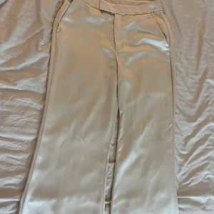 Satin byxor - Mycket bra skick, användes ett par gånger, funkar för både S och M, satin matrial, vida/raka byxor, krämvita färgen