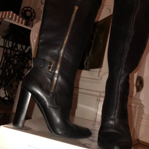 Skinnstövlar från Guess - Jättefina stövlar i mjukt skinn med gulddetaljer från Guess. Sparsamt använda och förvarade i originalkartong, som finns kvar så väl omhändertagna! Nypriset är ca 3000