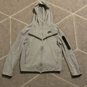 Nike tech/ Grå - Nike tack i grå är i bra form och är ej sönder elr sliten. Storlek 137-147 den är en 8/10, jag köpte den för 1000 från Nike… men säljer den för 400kr, om du har tåget eller ett annat pris?? Skriv till mig…..😃😄