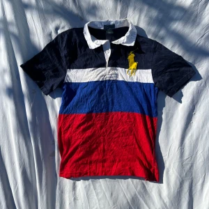 Pikétröja från Ralph Lauren - Säljer en snygg pikétröja från Ralph Lauren i storlek M. Tröjan är i bra skick förutom en liten fläck på kragen (syns på sista bilden).