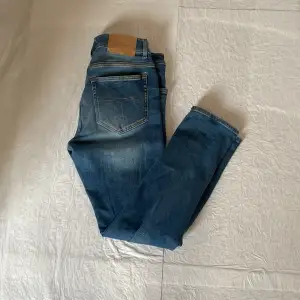 Jeans från tiger of Sweden, modell Slimfit. Det är två extremt små hål på övre sidan av bakfickorna. Tveka inte på att höra av dig vid fler frågor, pris kan diskuteras vid snabb affär!