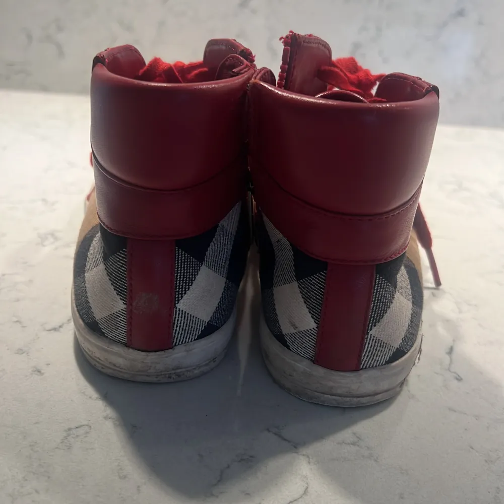 Säljer ett par röda sneakers från Burberry. Tydligt använda därav priset. . Skor.