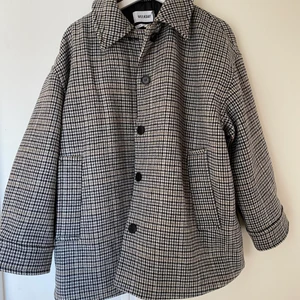 Rutig kappa Weekday - Perfekt vårkappa i beige/grått hundtandsmönster, storlek S. Modellen är lite oversized men ändå snygg. Jackan är i nyskick dvs oanvänd. Jag är 176cm lång. Nypris: 1000kr. Skriv för fler bilder!