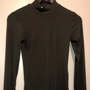 Body - Militärgrön body med liten krage, sitter ganska tajt och har två knappar att knäppa nertill