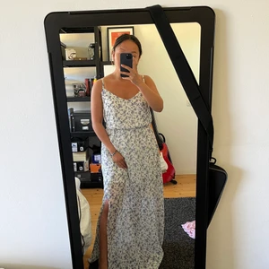 Jättefin vit långklänning med blommor,34 - Helt ny vit långklänning med lila små blommor i strl 34 / XS / S. Linne i toppen, med resår i midjan, vit underklänning och lång kjol i mesh. Med slits! 😍 Frakt 52kr