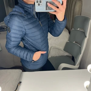 SailRacing dunjacka - Marinblå älta sailracing, dunjacka. Använd en del men i bra skick, värmande, två yttre fixkor med dragkedja och två innre fickor. Luva. Köpt på kvinnoavdelningen men finns samma modell för män. 