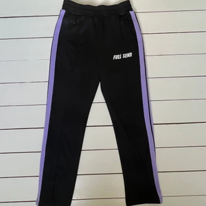 FULL SEND, M - Full Send byxor, storlek M Mycket bra skick.  Byxorna är gjorde i 100% polyester med två lila ”stripes” längst benen. 