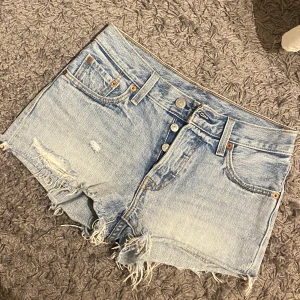 Levis Shorts - Levis Shorts (modell 501) i en ljusblå tvätt med lite slitningar. Superfina med väldigt bra passform, hittar tyvärr inte storlek men skulle säga att dom sitter som S. Aldrig använt pga fel storlek☺️