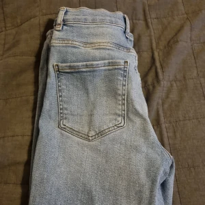 Jeans gina tricot storlek 34 - Säljer ett par jeans från gina tricot i storleken 34. Dom är nästan helt oanvända och har inga skador! Nypris 500!