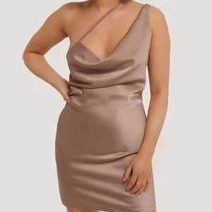 Klänning från NAKD strö 42 - Klänning från kollektionen med Chloé B med NAKD. Storlek 42, helt oanvänd endast testad. Då jag inte kan ha den så hittade jag bilden på modellen från nakds sida. Puderrosa silkigt material. Den har en dragkedja på sidan som gör det lättare att komma i klänningen. Klänningen har nästan ingen stretch, skulle säga att den är mer en 40 och för en person med mindre byst.