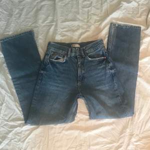 Ett par mom jeans fråg Gina tricot i storlek 32. De väldigt fint skick och säljes pågrund av att de är förkorta. Mått i midja: 70cm. Längd: 94 cm.