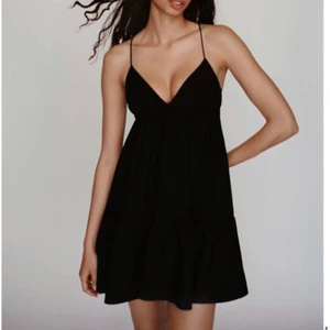 Svart poplinklänning - En svart poplinklänning med justerbart band i ryggen så att man kan spänna axelbanden. Använd endast en gång. 